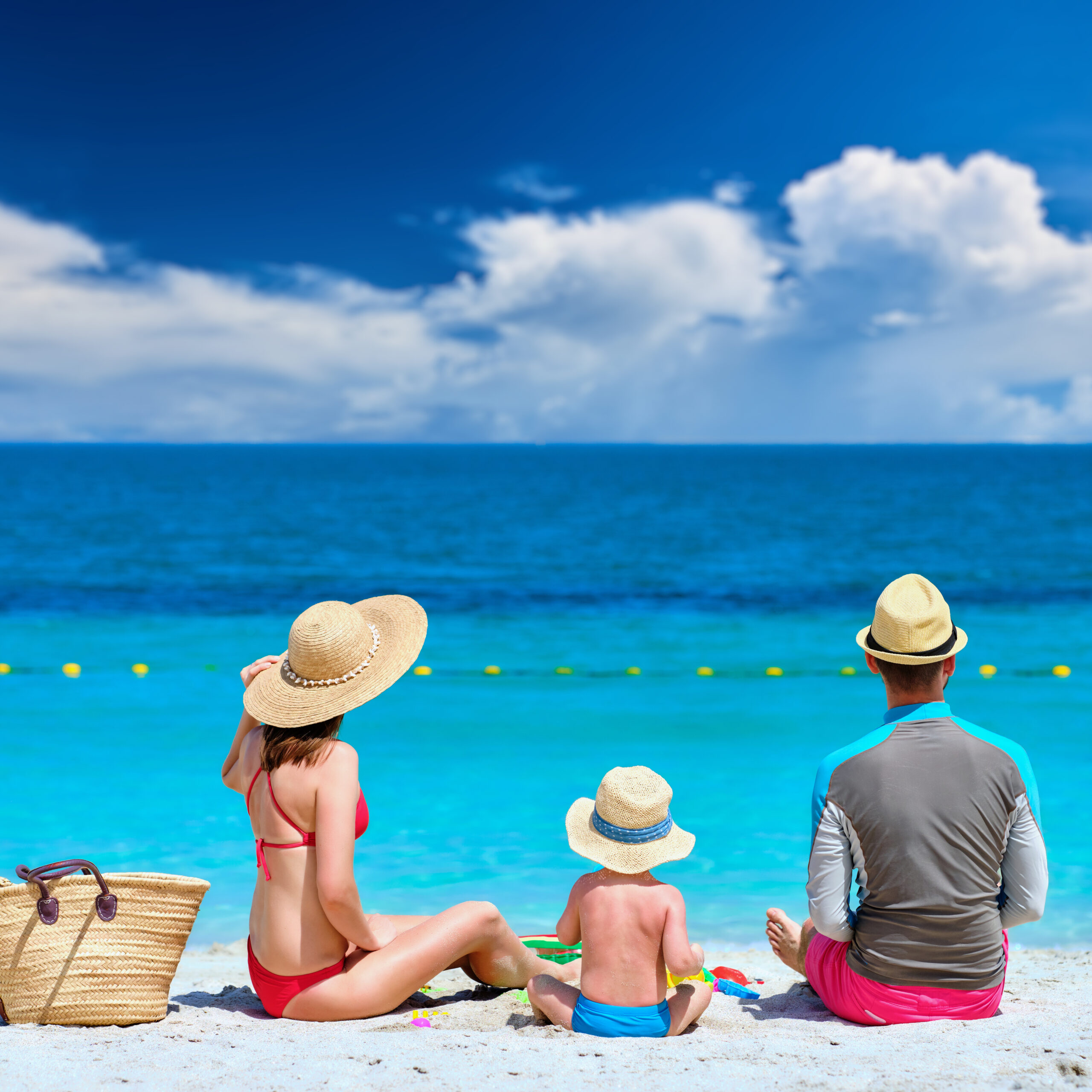 Family on beach. Two year old toddler boy playing with beach toys with mother and father on beach.